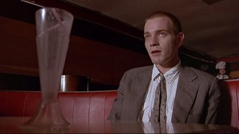Movie still from “Trainspotting” (1996), directed by Danny Boyle – A man sitting at a table in front of an empty glass; Close Up shot, Low angle