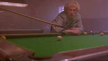 Movie still from “Trainspotting” (1996), directed by Danny Boyle – A man is playing a game of pool; Medium shot, Low angle