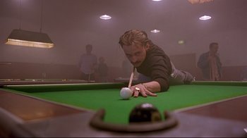 Movie still from “Trainspotting” (1996), directed by Danny Boyle – A man is playing a game of pool while holding a cue; Medium shot, Low angle