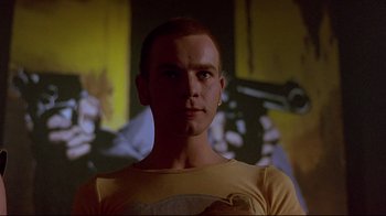 Movie still from “Trainspotting” (1996), directed by Danny Boyle – A man in a yellow t - shirt is in front of a projector; Close Up shot, Low angle