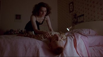 Movie still from “Trainspotting” (1996), directed by Danny Boyle – A woman is helping a man lay on a bed; Medium shot, Low angle