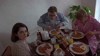 Movie still from “Trainspotting” (1996), directed by Danny Boyle – A group of people sitting at a table eating food; Medium shot, High angle