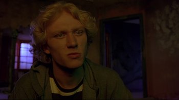 Movie still from “Trainspotting” (1996), directed by Danny Boyle – A man with blonde hair is looking at the camera; Close Up shot, Low angle