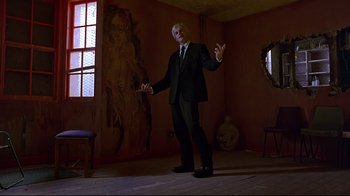 Movie still from “Trainspotting” (1996), directed by Danny Boyle – A man in a suit standing in an empty room; Wide shot, Low angle
