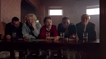 Movie still from “Trainspotting” (1996), directed by Danny Boyle – A group of people sitting at a table with glasses of beer; Medium shot, Low angle