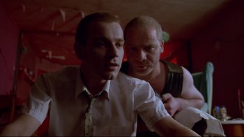 Movie still from “Trainspotting” (1996), directed by Danny Boyle – Two men posing for a picture in front of a red wall; Close Up shot, Low angle