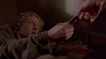 Movie still from “Trainspotting” (1996), directed by Danny Boyle – A man holding a pair of scissors up to his face; Close Up shot, High angle