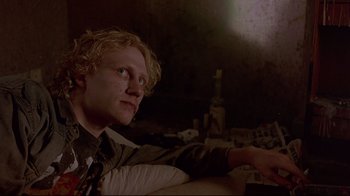 Movie still from “Trainspotting” (1996), directed by Danny Boyle – A man sitting on a couch looking up at the sky; Medium shot, Low angle