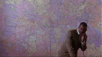 A man leaning against a wall in front of a map