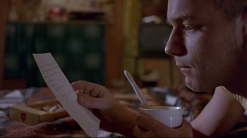 Movie still from “Trainspotting” (1996), directed by Danny Boyle – A man sitting at a table looking at a piece of paper; Close Up shot, Low angle