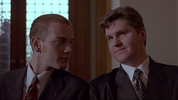 Movie still from “Trainspotting” (1996), directed by Danny Boyle – Two men in suits looking at each other in front of a window; Close Up shot, Low angle