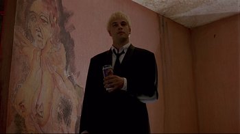Movie still from “Trainspotting” (1996), directed by Danny Boyle – A man in a black suit holding a can of beer; Medium shot, Low angle
