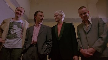 Movie still from “Trainspotting” (1996), directed by Danny Boyle – A group of men standing next to each other in a room; Medium shot, Low angle