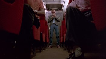 Movie still from “Trainspotting” (1996), directed by Danny Boyle – A man standing on a train with his hands to his mouth; Wide shot, Low angle