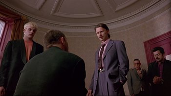 Movie still from “Trainspotting” (1996), directed by Danny Boyle – A man in a suit and tie standing next to another man in a suit; Medium shot, Low angle