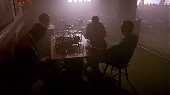 Movie still from “Trainspotting” (1996), directed by Danny Boyle – A group of people sitting at a table with drinks; Wide shot, Low angle