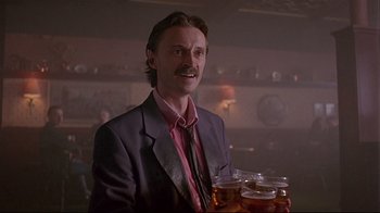 Movie still from “Trainspotting” (1996), directed by Danny Boyle – A man in a suit and tie holding a tray of drinks; Medium shot, Low angle
