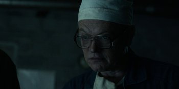 Movie still from “Chernobyl” (2019), directed by Johan Renck – An older man wearing glasses and a white hat; Close Up shot, Low angle