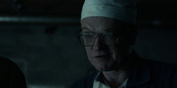 Movie still from “Chernobyl” (2019), directed by Johan Renck – An older man wearing glasses and a white hat; Close Up shot, Over the shoulder angle