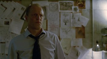 Movie still from “True Detective” (2014), created by Issa López – A man standing in front of a wall covered with drawings; Medium shot, Over the shoulder angle