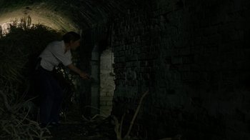 Movie still from “True Detective” (2014), created by Issa López – A person is standing in a dark tunnel; Wide shot, Low angle