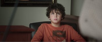 Movie still from “99 Homes” (2014), directed by Ramin Bahrani – A young boy sitting in a chair looking up at the sky; Close Up shot, Low angle