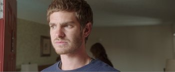 Movie still from “99 Homes” (2014), directed by Ramin Bahrani – A person wearing a blue t - shirt; Close Up shot, Over the shoulder angle