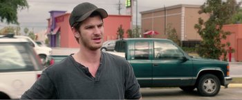 Movie still from “99 Homes” (2014), directed by Ramin Bahrani – A man wearing a baseball cap standing in front of a green truck; Close Up shot, Over the shoulder angle