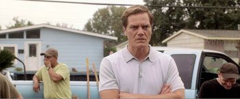 Movie still from “99 Homes” (2014), directed by Ramin Bahrani – A person with his arms crossed; Close Up shot, Over the shoulder angle