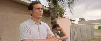 Movie still from “99 Homes” (2014), directed by Ramin Bahrani – A man standing next to another man in a white shirt; Close Up shot, Low angle