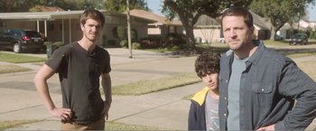 Movie still from “99 Homes” (2014), directed by Ramin Bahrani – A group of young men standing on a sidewalk; Medium shot, Over the shoulder angle
