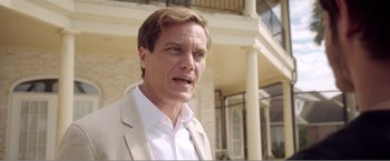 Movie still from “99 Homes” (2014), directed by Ramin Bahrani – A person wearing a suit and tie; Close Up shot, Low angle