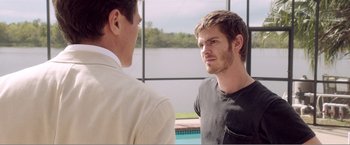 Movie still from “99 Homes” (2014), directed by Ramin Bahrani – Two men standing next to each other in front of a pool; Medium shot, Over the shoulder angle