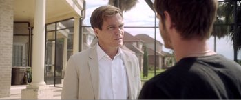 Movie still from “99 Homes” (2014), directed by Ramin Bahrani – A man wearing a suit talking to another man outside; Medium shot, Over the shoulder angle