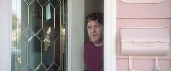 Movie still from “99 Homes” (2014), directed by Ramin Bahrani – A person standing in a doorway; Close Up shot, Low angle
