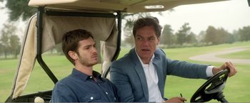 Movie still from “99 Homes” (2014), directed by Ramin Bahrani – Two men sitting in the back of a golf cart on a golf course; Close Up shot, Over the shoulder angle