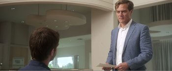 Movie still from “99 Homes” (2014), directed by Ramin Bahrani – A man in a blue suit is looking at another man in a white shirt; Medium shot, Over the shoulder angle