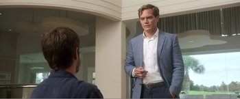 Movie still from “99 Homes” (2014), directed by Ramin Bahrani – A man standing in front of a mirror talking to another man; Medium shot, Over the shoulder angle