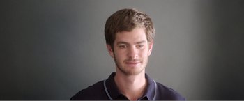 Movie still from “99 Homes” (2014), directed by Ramin Bahrani – A young man with a beard is smiling for the camera; Close Up shot, Low angle