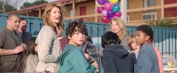 Movie still from “99 Homes” (2014), directed by Ramin Bahrani – A group of people standing next to each other near a building; Medium shot, Over the shoulder angle