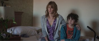 Movie still from “99 Homes” (2014), directed by Ramin Bahrani – A woman sitting on a bed next to a boy; Medium shot, Over the shoulder angle