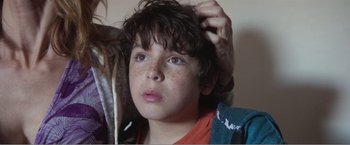 Movie still from “99 Homes” (2014), directed by Ramin Bahrani – A young boy is combing his hair with a brush; Close Up shot, Low angle