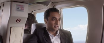 Movie still from “99 Homes” (2014), directed by Ramin Bahrani – A man in a suit and tie sitting in a plane; Medium shot, Over the shoulder angle