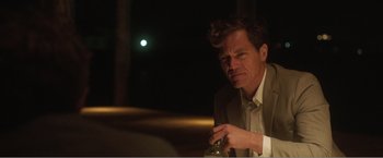 Movie still from “99 Homes” (2014), directed by Ramin Bahrani – A man sitting at a table with a bottle in front of him; Close Up shot, Over the shoulder angle