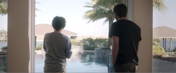 Movie still from “99 Homes” (2014), directed by Ramin Bahrani – Two young men looking out over a pool; Wide shot, Over the shoulder angle