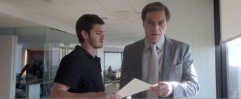 Movie still from “99 Homes” (2014), directed by Ramin Bahrani – A man and a man looking at a piece of paper in an office; Medium shot, Over the shoulder angle