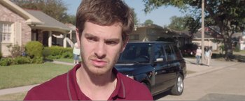 Movie still from “99 Homes” (2014), directed by Ramin Bahrani – A man standing in front of a black car; Close Up shot, Over the shoulder angle