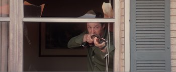 Movie still from “99 Homes” (2014), directed by Ramin Bahrani – A man is holding a gun in his hand; Medium shot, Over the shoulder angle