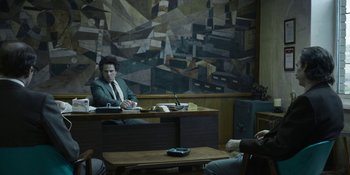 Movie still from “Chernobyl” (2019), directed by Johan Renck – A man sitting at a desk in front of a painting; Wide shot, Over the shoulder angle