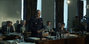 Movie still from “Chernobyl” (2019), directed by Johan Renck – A man standing at a table in front of other men; Medium shot, Low angle